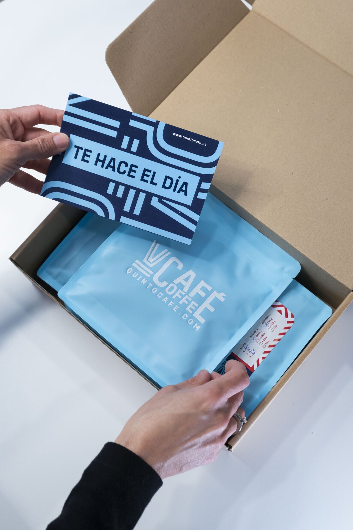 Quinto Café subscription box with the "Te hace el día" card and bags of coffee